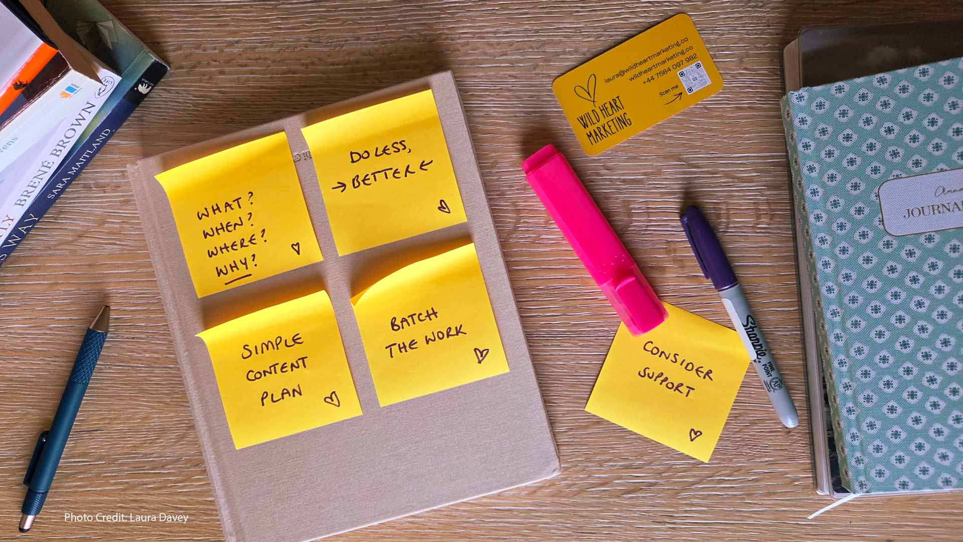 Books, pens, notebooks and handwritten post-it notes with marketing tips on laid out on a desk